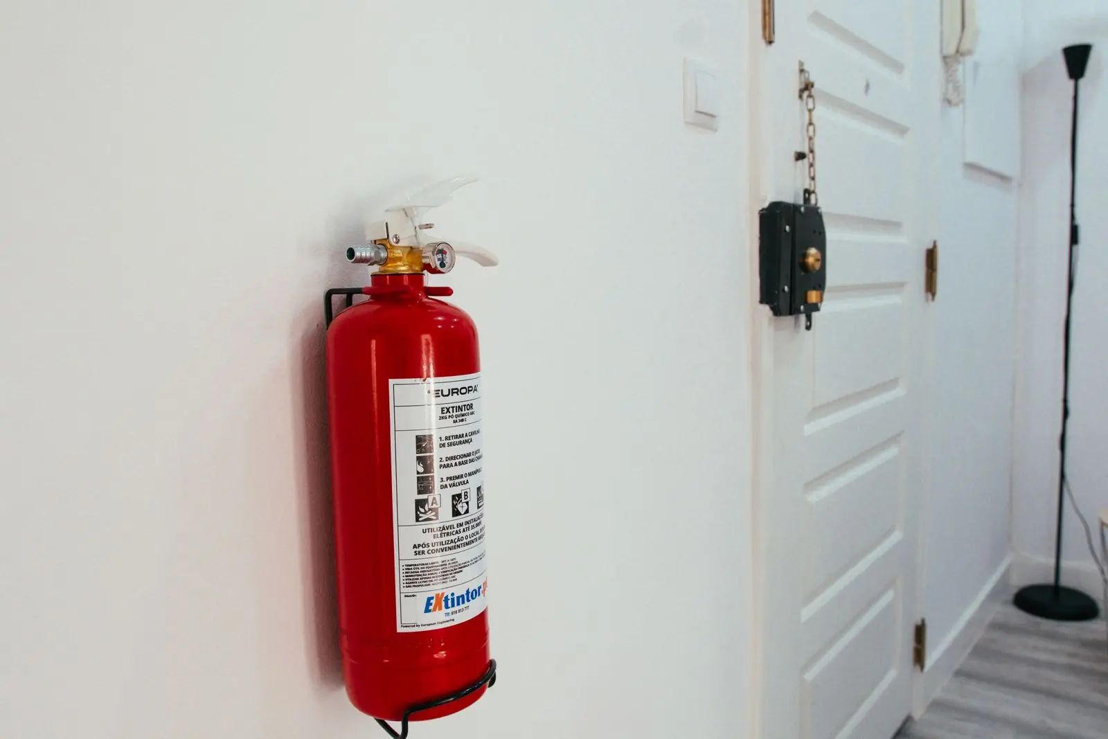 Fire extinguisher mounted on a hallway wall beside a door in a residence