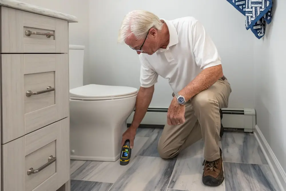 Inspector checking a bathroom floor for moisture